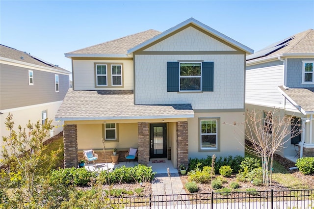 craftsman-style home with a shingled roof and fence