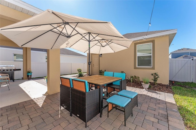 view of patio featuring outdoor dining space, grilling area, and fence