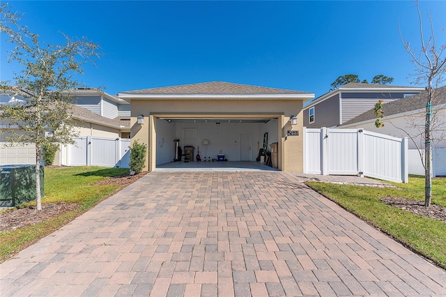 view of front of property featuring an attached garage, fence, decorative driveway, and stucco siding