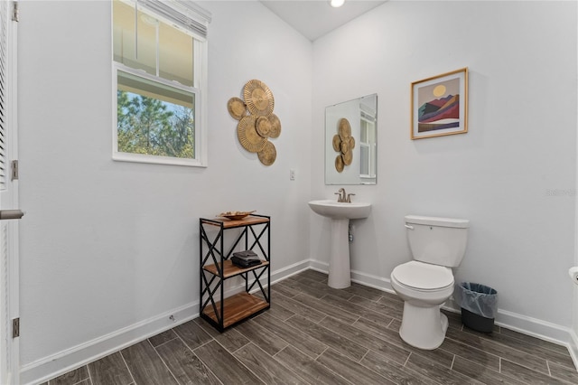 half bath featuring toilet, baseboards, and wood finish floors