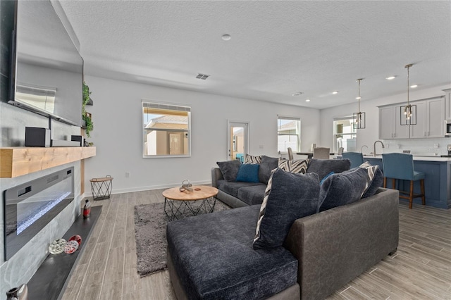 living room with light wood finished floors, baseboards, and a textured ceiling