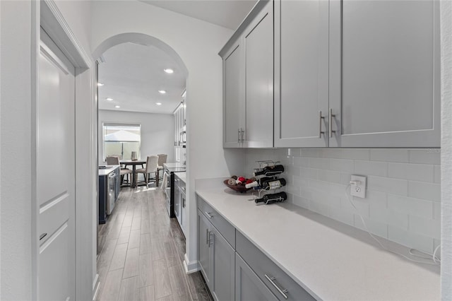 bar with arched walkways, stainless steel electric range oven, recessed lighting, backsplash, and wood finished floors