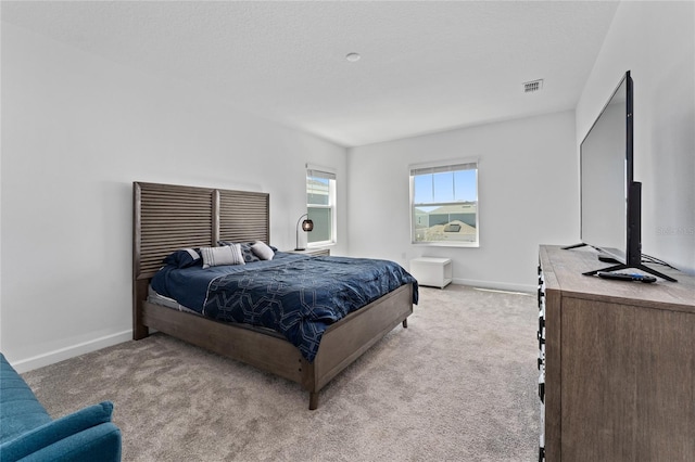 bedroom featuring light carpet, visible vents, baseboards, and a textured ceiling