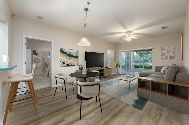 living area with visible vents, ceiling fan, light wood-style flooring, and a textured ceiling