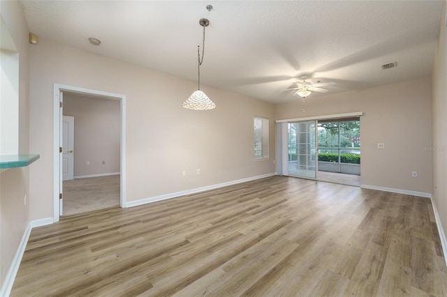 unfurnished room featuring baseboards, visible vents, ceiling fan, a textured ceiling, and light wood-type flooring