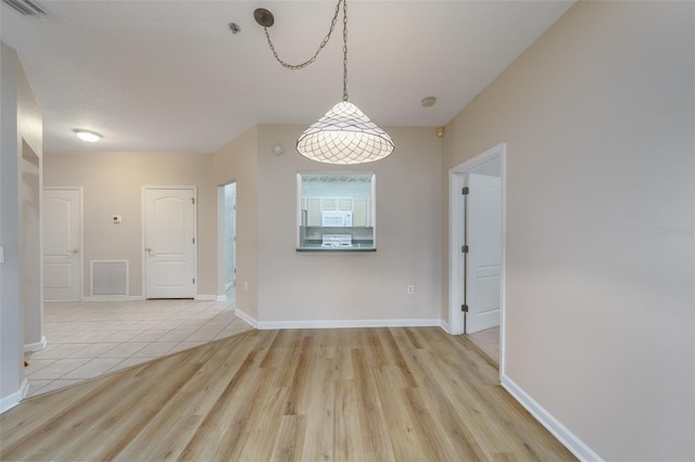 unfurnished dining area with visible vents, light wood-style flooring, and baseboards