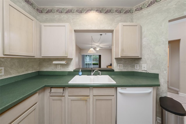 kitchen featuring dark countertops, white dishwasher, a sink, and decorative backsplash