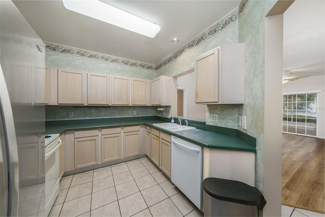 kitchen with white appliances, dark countertops, a sink, and light tile patterned flooring