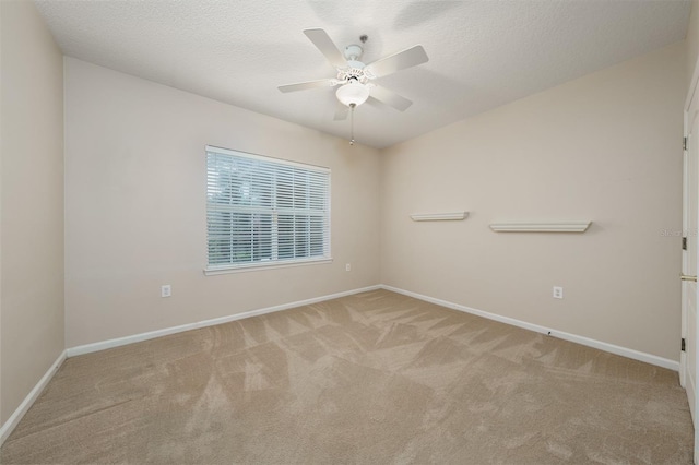 unfurnished room featuring light carpet, ceiling fan, a textured ceiling, and baseboards