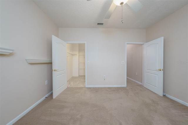 unfurnished bedroom featuring a textured ceiling, baseboards, visible vents, and light colored carpet