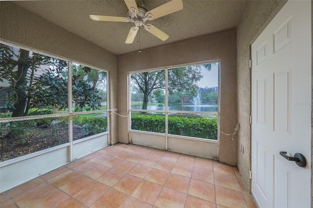 unfurnished sunroom with a ceiling fan and a water view