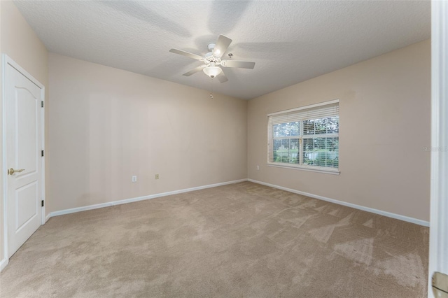 empty room with carpet floors, ceiling fan, baseboards, and a textured ceiling