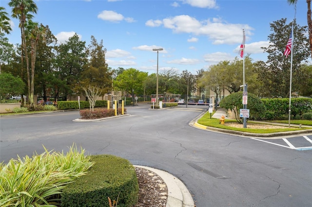 view of street with traffic signs, a gate, a gated entry, and curbs