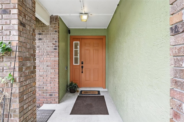 doorway to property with brick siding and stucco siding