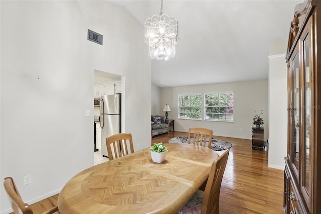 dining space with light wood-style floors, visible vents, baseboards, and an inviting chandelier