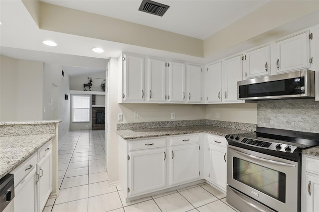 kitchen featuring a fireplace, visible vents, appliances with stainless steel finishes, white cabinets, and light stone countertops