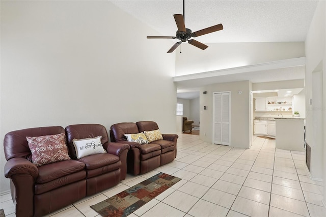 living area featuring light tile patterned floors, visible vents, ceiling fan, vaulted ceiling, and a textured ceiling