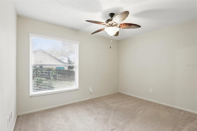 carpeted spare room featuring baseboards, a ceiling fan, and a textured ceiling