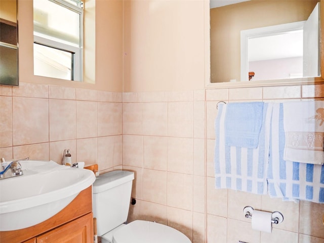 bathroom with tile walls, toilet, and vanity