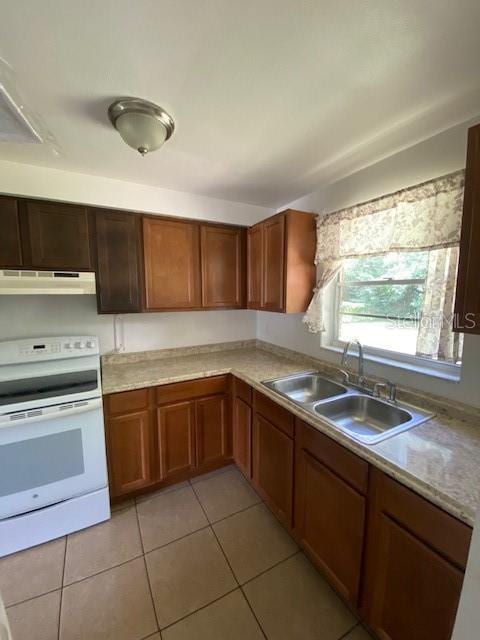 kitchen featuring white electric range oven, brown cabinetry, light countertops, under cabinet range hood, and a sink