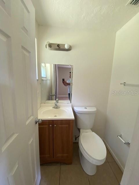 bathroom with toilet, vanity, baseboards, and tile patterned floors