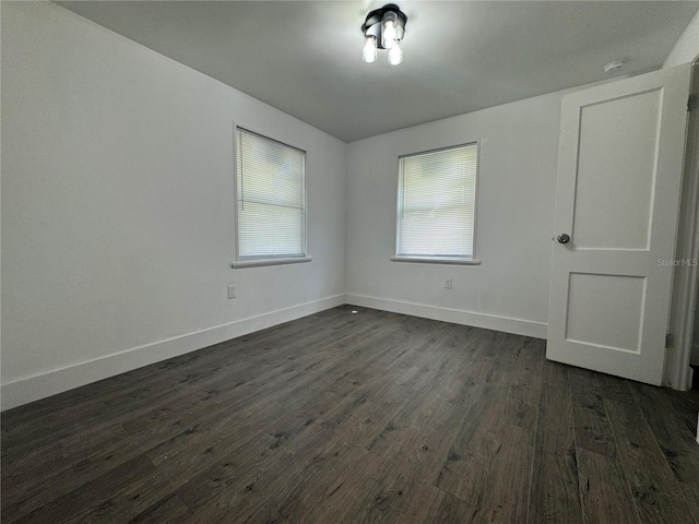 empty room featuring dark wood-style flooring and baseboards