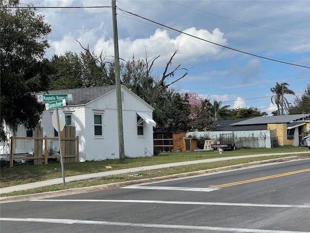 view of home's exterior with fence, concrete block siding, and a lawn