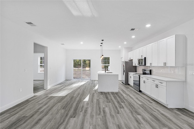 kitchen featuring light countertops, appliances with stainless steel finishes, white cabinetry, and pendant lighting