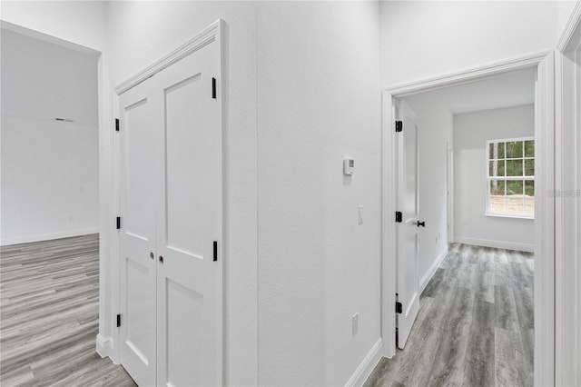 hall featuring light wood finished floors and baseboards