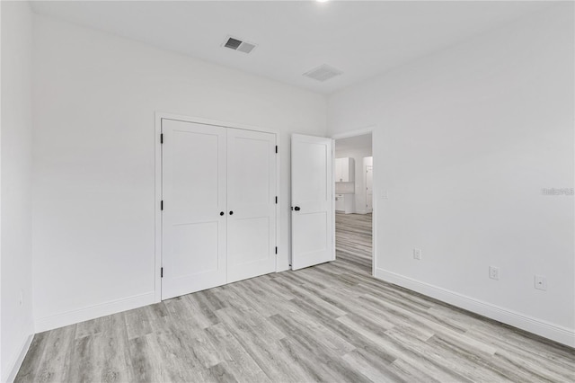 unfurnished bedroom featuring light wood-style floors, a closet, visible vents, and baseboards