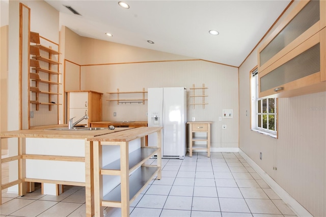 kitchen with light tile patterned floors, visible vents, lofted ceiling, white fridge with ice dispenser, and a sink