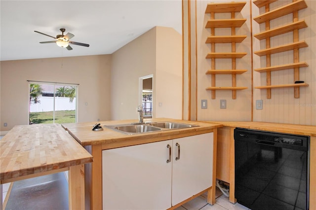 kitchen featuring lofted ceiling, wooden counters, white cabinets, a sink, and dishwasher