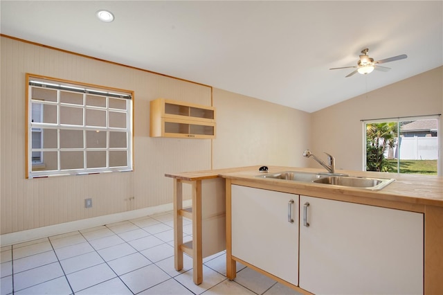 kitchen with butcher block counters, light tile patterned flooring, vaulted ceiling, a sink, and ceiling fan