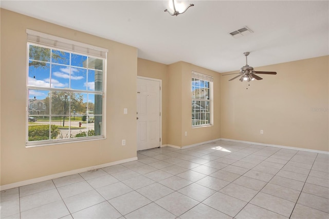 empty room featuring light tile patterned floors, baseboards, visible vents, and ceiling fan