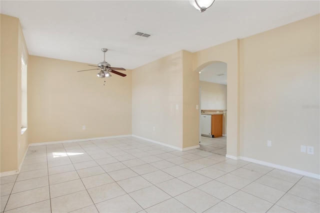 spare room with arched walkways, light tile patterned floors, visible vents, baseboards, and a ceiling fan