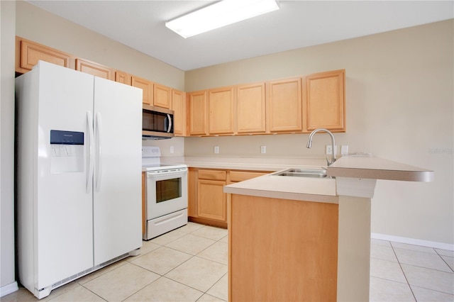 kitchen with a peninsula, white appliances, a sink, and light brown cabinetry