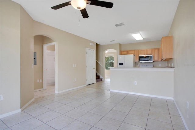 kitchen with light brown cabinets, visible vents, stainless steel microwave, white fridge with ice dispenser, and light tile patterned flooring