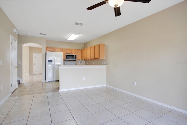 kitchen featuring arched walkways, light tile patterned flooring, white refrigerator with ice dispenser, visible vents, and stainless steel microwave