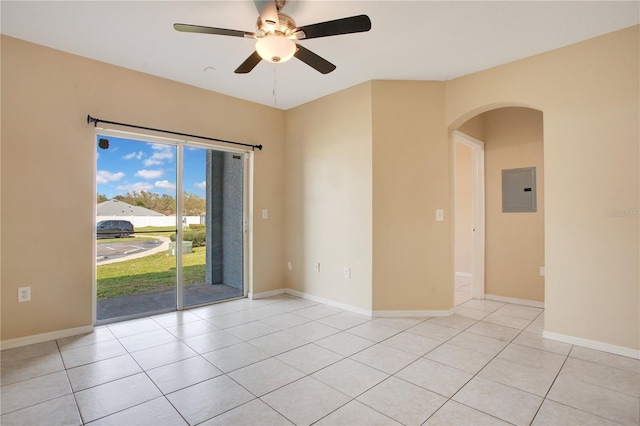 unfurnished room featuring arched walkways, a ceiling fan, light tile patterned flooring, electric panel, and baseboards