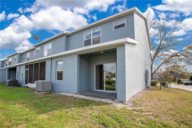 rear view of house featuring stucco siding, central AC unit, and a yard