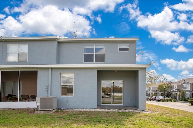 rear view of property with stucco siding, a yard, and central AC unit