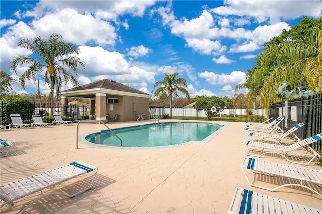 community pool with a patio area and fence