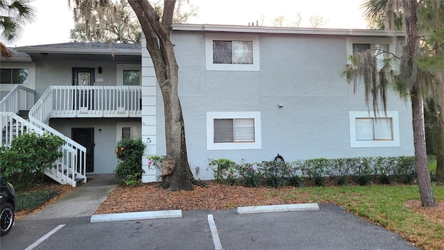 view of property with stairs and uncovered parking