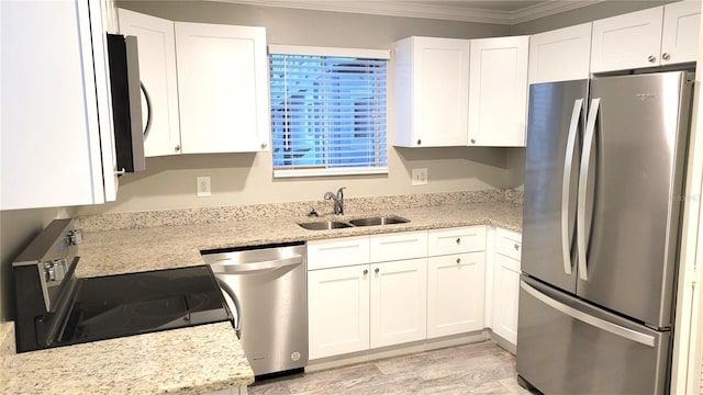 kitchen with appliances with stainless steel finishes, ornamental molding, white cabinets, a sink, and light stone countertops