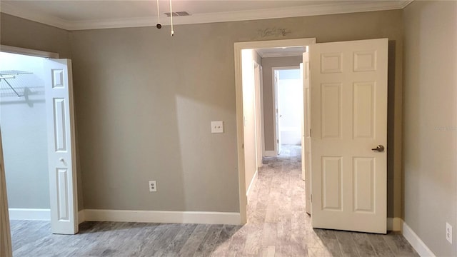 unfurnished room featuring light wood-type flooring, baseboards, visible vents, and ornamental molding