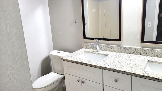 bathroom featuring double vanity, toilet, and a sink