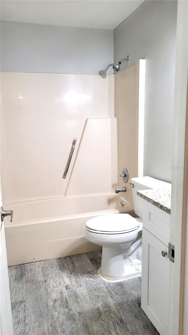 full bathroom with washtub / shower combination, vanity, toilet, and wood finished floors