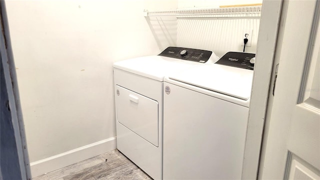 clothes washing area featuring baseboards, laundry area, washing machine and dryer, and light wood-style floors