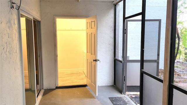 corridor featuring a textured wall, plenty of natural light, and concrete floors