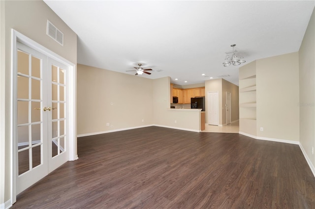 unfurnished living room featuring baseboards, visible vents, dark wood-type flooring, and ceiling fan with notable chandelier